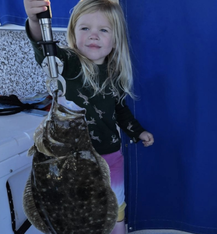 Young blonde girl holding a fish as big as her